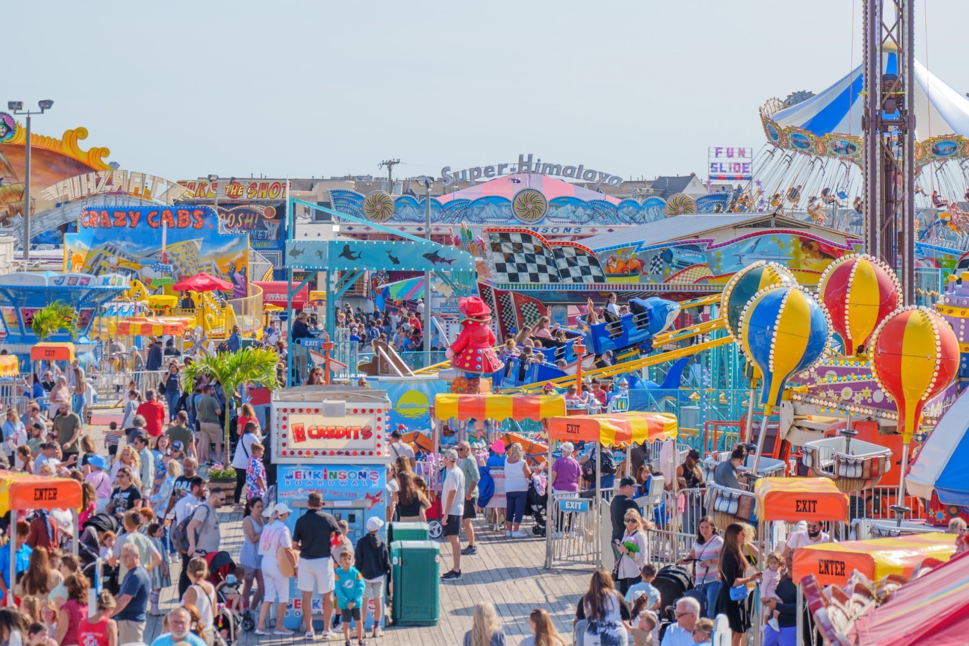 A vibrant scene at Jenkinson's Boardwalk with colorful rides, games, and a lively crowd enjoying the amusement park.